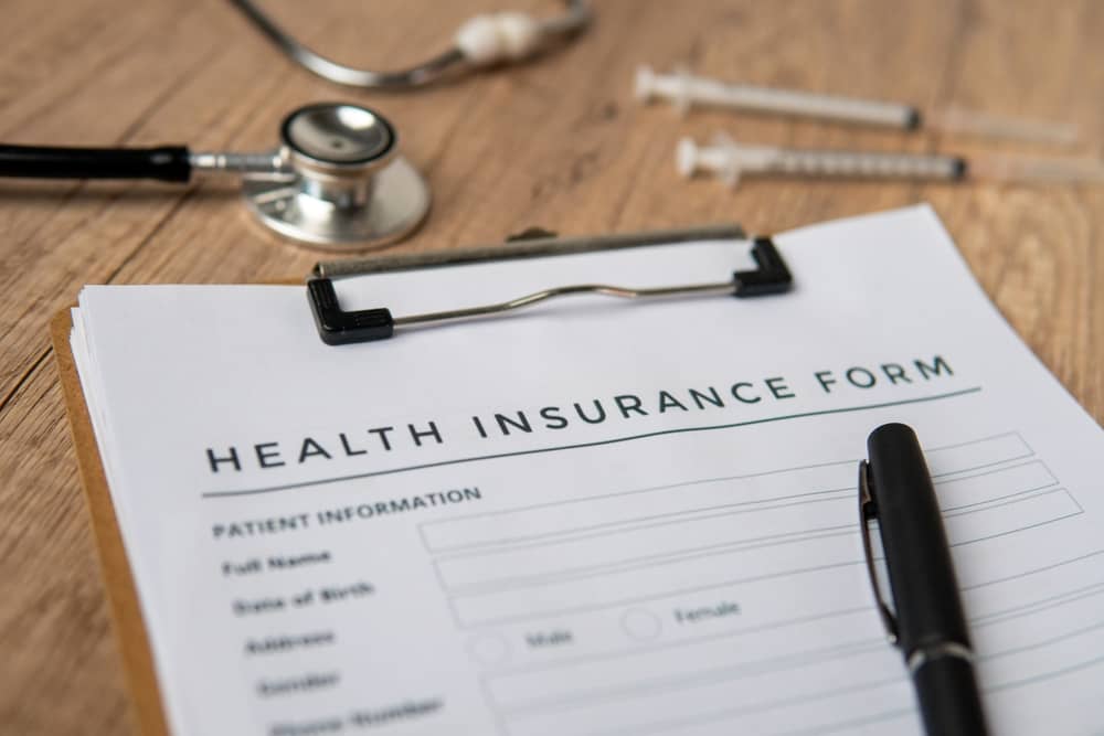 Medical insurance form on clipboard with stethoscope and pen for breast surgery coding and coverage guide by registered nurse