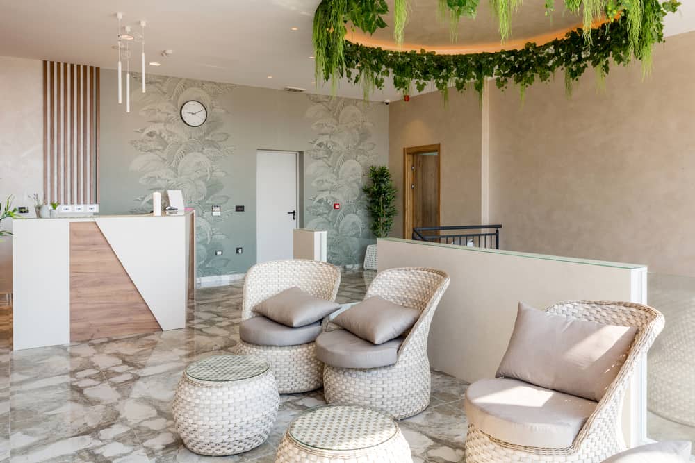 Luxury medical spa reception area with modern wicker seating, botanical wall art, and upscale interior design showcasing premium aesthetic clinic environment