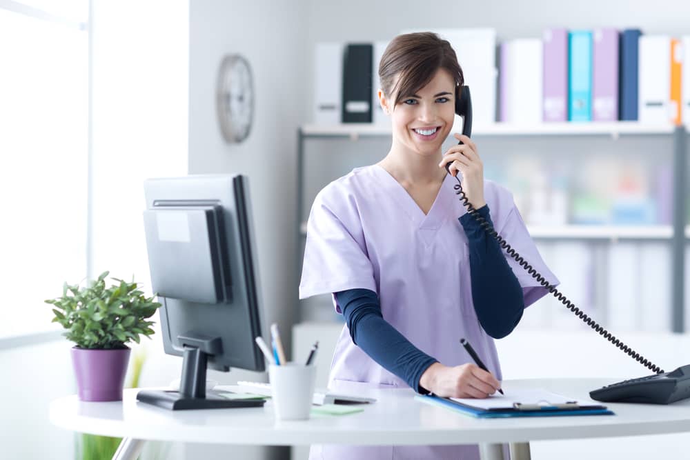 Smiling medical professional answering consultation phone call in modern healthcare office setting