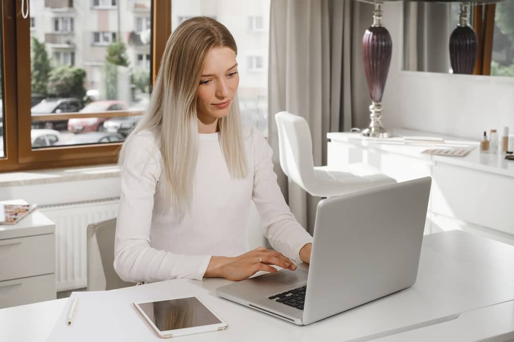 Medical spa owner working on laptop creating marketing content in modern aesthetic clinic office