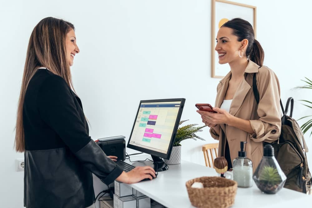 Med spa receptionist helping client schedule appointment using online booking system