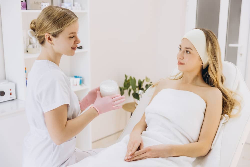 Licensed aesthetician consulting with patient about anti-aging neurocosmetic skincare protocol in clean, professional medical spa treatment room