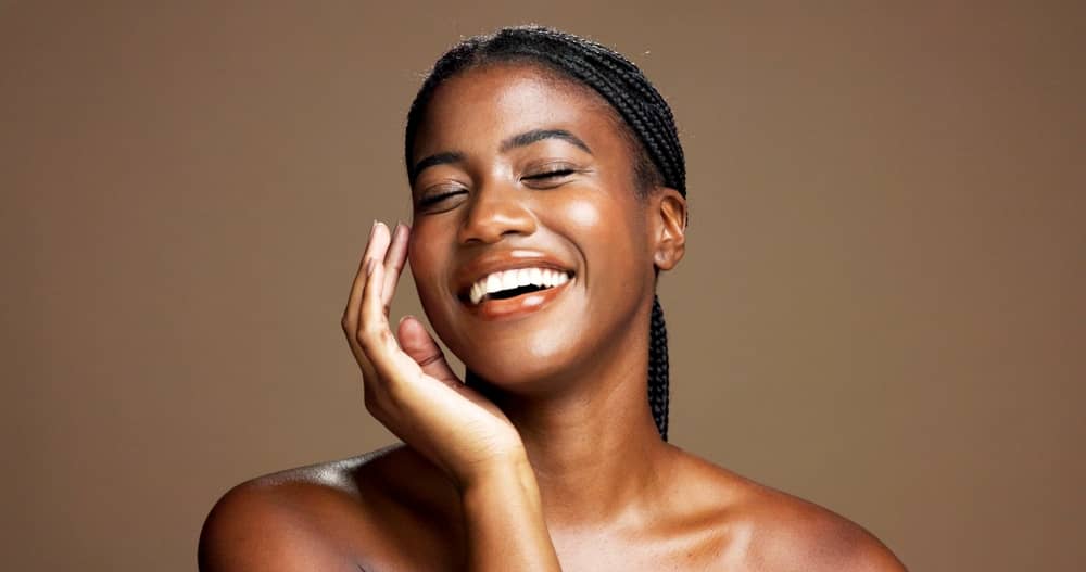 Smiling Black woman with glowing healthy skin after safe laser treatment for dark skin tones
