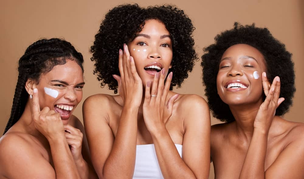 Happy Black women with radiant melanin-rich skin following gentle skincare routine after safe laser treatment
